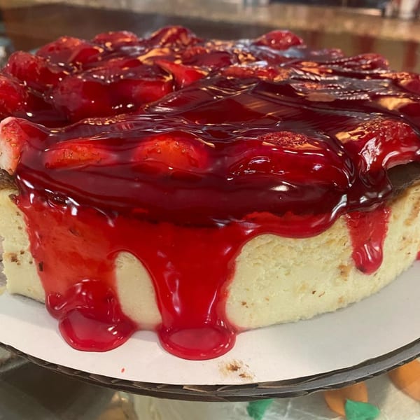 A whole strawberry cheesecake from Morristown Diner, topped with glistening red glaze and fresh berries.